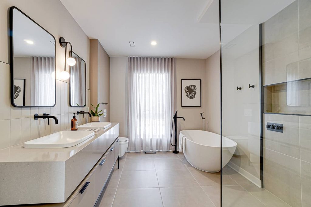 Salle de bain design avec double vasque, bain autoportant blanc et robinetterie noire mate — design d'intérieur Montréal