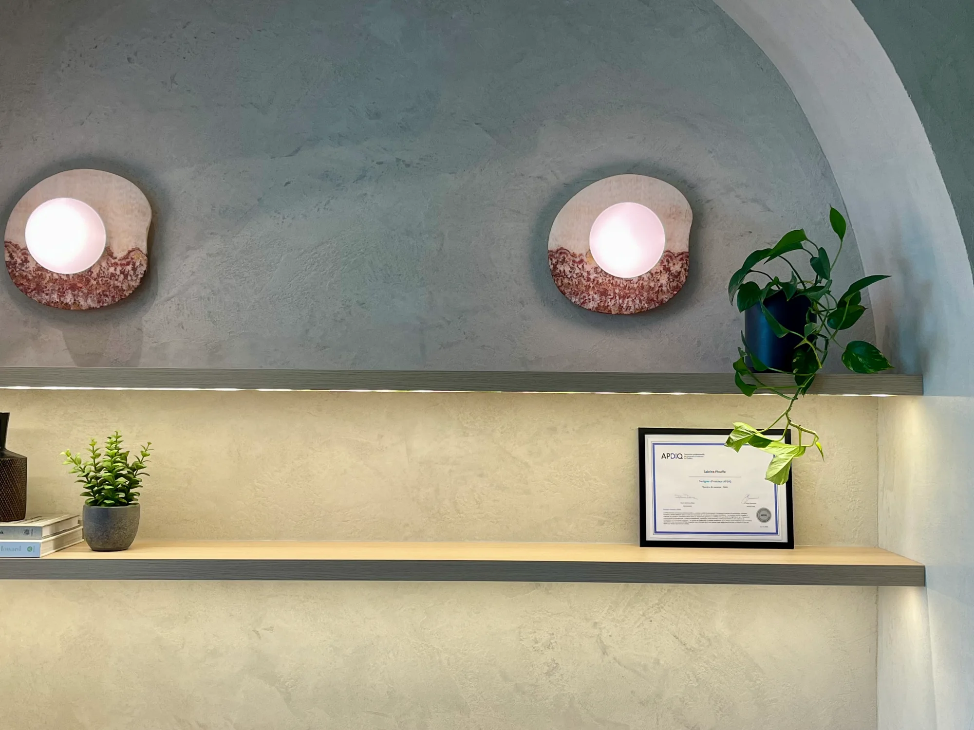 Certificat APDIQ de designer d'intérieur encadré sur une étagère au bureau de Groupe Cartier, entouré de plantes et de livres