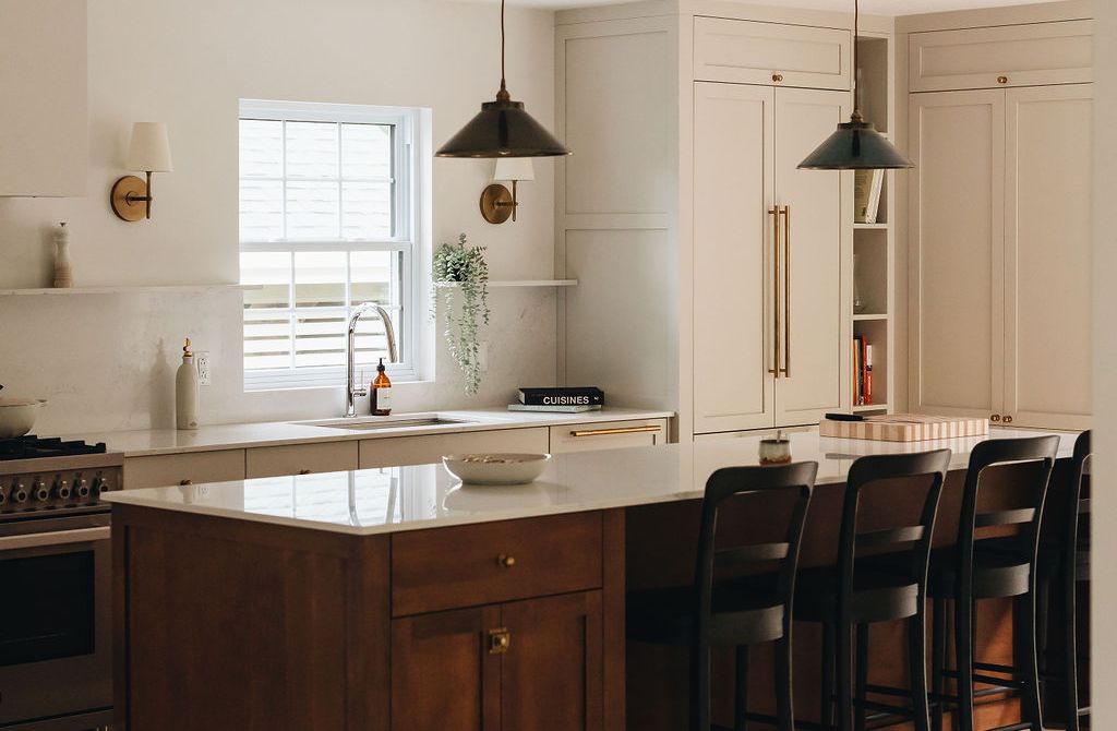 Renovated kitchen with a dark wood island and white cabinetry