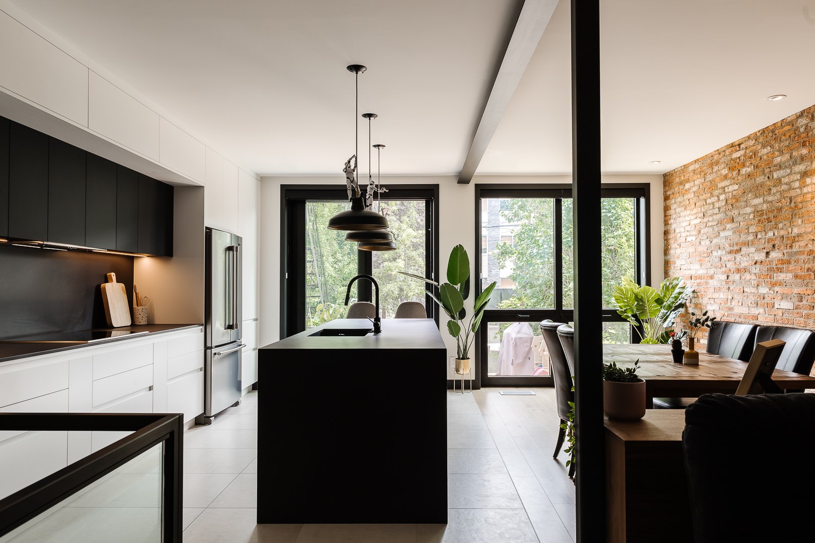Cuisine sur mesure avec îlot noir, armoires blanches et noires et mur de briques, Résidence Lanaudière, Montréal