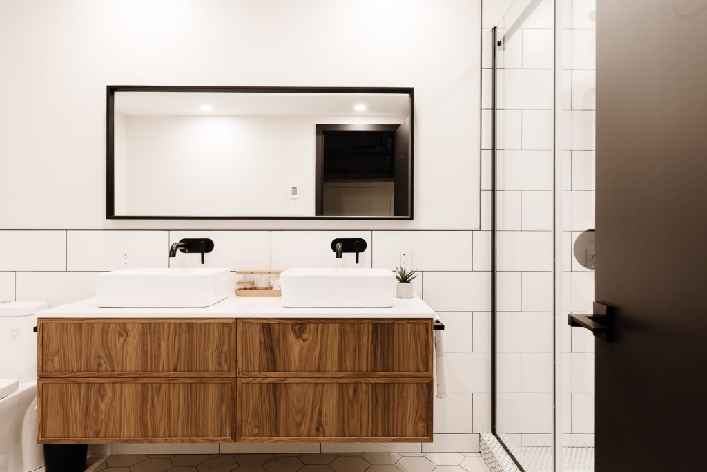 Salle de bain avec vanité double suspendue en bois, murs en carreaux blancs et robinetterie noire, Résidence Lanaudière, Montréal