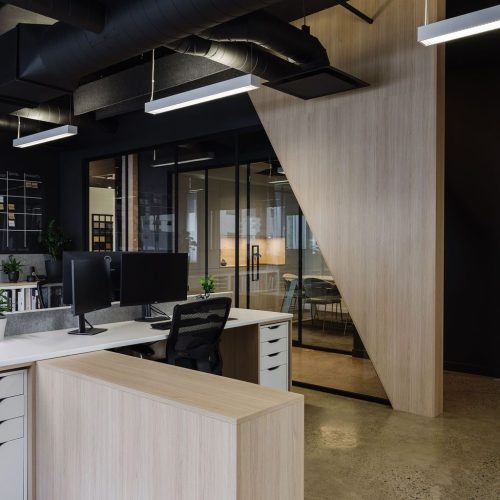 Espace bureau commercial à aire ouverte avec cloisons en bois clair et plancher de béton poli